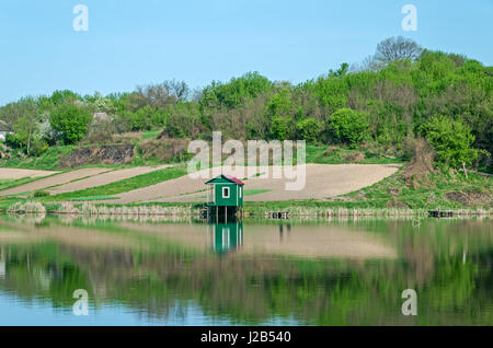 Piccola pesca capanno sulla riva rurale di stagno in primavera Foto Stock