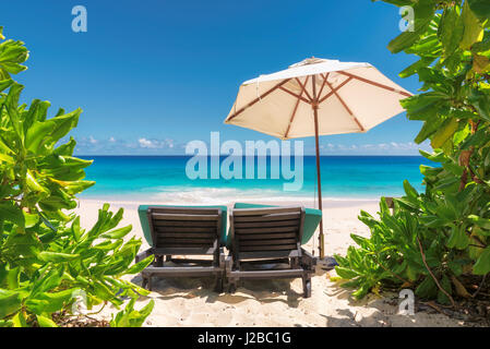 Vista sull'oceano incredibile spiaggia con sabbia bianca, trasparenti acque turchesi e ombrellone e sdraio sulla spiaggia. Foto Stock