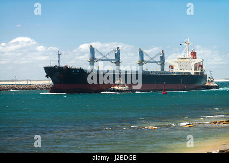 Una grande nave di carbone passa Nobbys testa come si lascia l'Oceano Pacifico ed entra nel porto di Newcastle e il Cacciatore estuario del fiume, NSW, Australia. Foto Stock