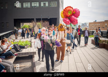 L'artista brasiliano, André Feliciano, destra, noto come "arte giardiniere' passeggiate lungo la linea alta Park di New York assistita dal regista brasiliano Caru Alves, centro e artista Nancy Prusinowski, sinistra, Domenica, 23 aprile 2017 la distribuzione di palloncini e fiori a passante nelle sue prestazioni pezzo di arte, il Floraissance parade. Il Floraissance è un'arte movimento creato da Feliciano basata sull'idea che l'attuale non è in grado di descrivere la tecnica più e abbiamo arte in movimento nella fase successiva, crescendo come i fiori nel Floraissance. (© Richard B. Levine) Foto Stock