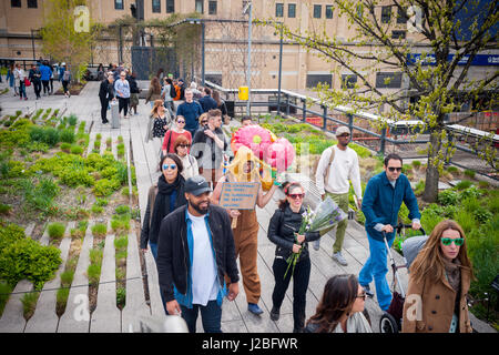 L'artista brasiliano, André Feliciano, centro noto come "arte giardiniere' passeggiate lungo la linea alta Park di New York assistita dal regista brasiliano Caru Alves, destra, Domenica, 23 aprile 2017 la distribuzione di palloncini e fiori a passante nelle sue prestazioni pezzo di arte, il Floraissance parade. Il Floraissance è un'arte movimento creato da Feliciano basata sull'idea che l'attuale non è in grado di descrivere la tecnica più e abbiamo arte in movimento nella fase successiva, crescendo come i fiori nel Floraissance. (© Richard B. Levine) Foto Stock