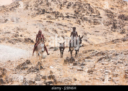 Africa, Namibia, Northwestern Namibia. Due giovani ragazze Himba asini di equitazione. Foto Stock