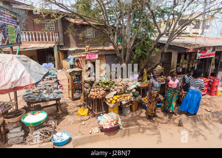 Africa, Sierra Leone, Freetown. La donna in piedi di fronte a un mercato alimentare. Foto Stock