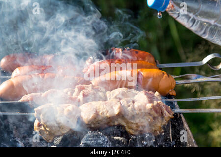 La frittura shish kebab e salsicce alla griglia sulla griglia sui carboni ardenti Foto Stock