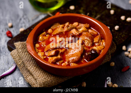 Primo piano di un vaso di terracotta con lo spagnolo callos, un tipico stufato di trippa di manzo e ceci, su una tavola in legno rustico Foto Stock