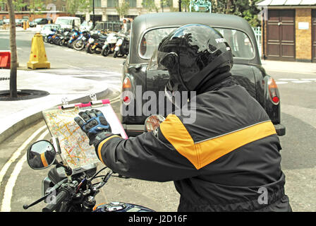 Il tassista di colore tirocinante si è seduto in moto a controllare strade e percorsi sulla mappa stradale A-Z in preparazione del test di conoscenza della capitale di Londra Inghilterra Regno Unito Foto Stock