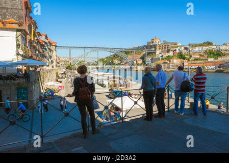 Porto Portugal Ribeira, vista dei turisti che guardano lungo il lungomare di Ribeira con il ponte Dom Luis i e lo skyline di Gaia in lontananza, Portogallo Foto Stock