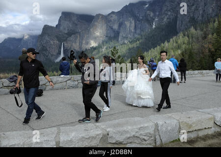 Parco Nazionale di Yosemite, CA, Stati Uniti d'America. 26 apr, 2017. Molto più grande del normale nevicata oltre l'inverno del 2016-2017 sinistra Yosemite National Park con una sovrabbondanza di acqua e diverse chiusure della strada nella valle l'ingresso meridionale e la strada che conduce alla valle di Yosemite riapriranno lunedì 1 maggio 2017. Rovere Biig strada piana era stato impraticabile per due mesi a causa di una frana, costringendo i viaggiatori a prendere un 22-Mile deviazione. I fotografi con la loro sposa e lo sposo client nel traino di finire le riprese presso la Galleria area di visualizzazione all'ingresso al Parco Nazionale di Yosemite Valley con Bridal Veil Falls in background. Foto Stock