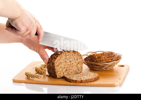 Pane fresco. La Crusca per affettare il pane su un tagliere. taglio mani il pane sulla tavola di legno Foto Stock