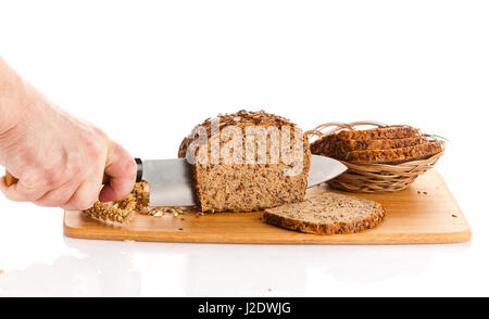 Pane fresco. La Crusca per affettare il pane su un tagliere. taglio mani il pane sulla tavola di legno Foto Stock