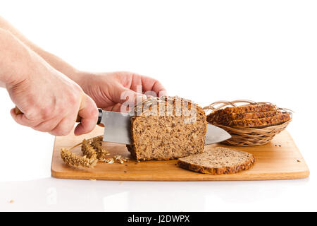 Pane fresco. La Crusca per affettare il pane su un tagliere. taglio mani il pane sulla tavola di legno Foto Stock