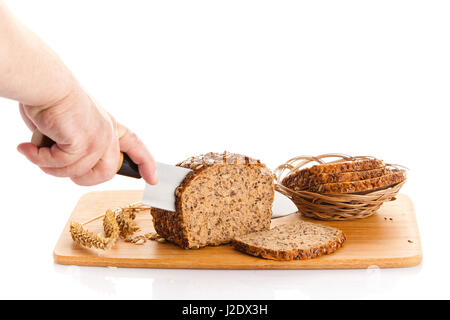 Pane fresco. La Crusca per affettare il pane su un tagliere. taglio mani il pane sulla tavola di legno Foto Stock