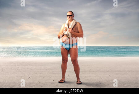 Uomo grasso permanente sulla spiaggia Foto Stock