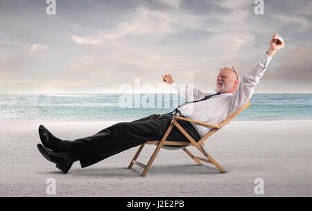 Il vecchio uomo d affari rilassante sulla spiaggia Foto Stock