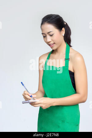 Imprenditrice con grembiule verde guarnitura a dimenticare la lista con nota e penna Foto Stock