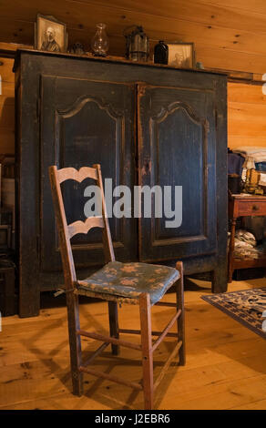 Sedia antica, blu comò in legno decorato con cornici, lampade a olio nella camera da letto principale sul pavimento del piano superiore all'interno di un vecchio 1840s Canadiana house Foto Stock