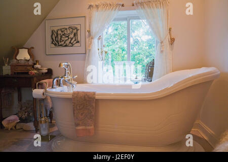 Antica vasca da bagno su base rialzata in bagno sul pavimento del piano superiore all'interno di un vecchio 1809 cottage in stile casa residenziale Foto Stock