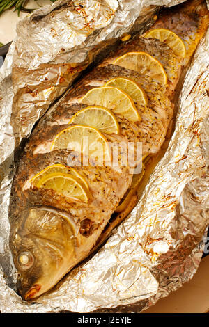 Carpa fritta con succo di limone, lime e le erbe in lamina Foto Stock