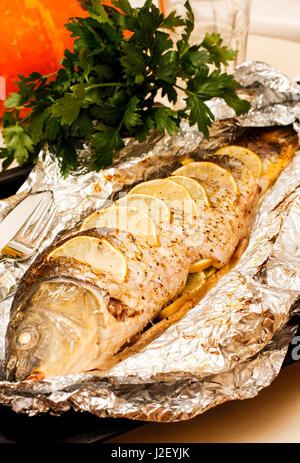 Carpa fritta con limone, calce e erbe sulla lamina Foto Stock