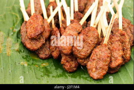 Chiudere la carne di maiale grill con bastone di legno famosi fast finger food in Thailandia il banana leaf Foto Stock