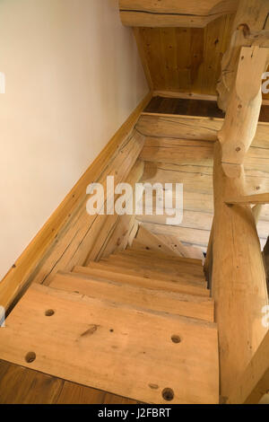 Scala in legno di pino orientale bianca che porta al piano inferiore all'interno di una lussuosa casa in legno in stile cottage scandinavo. Foto Stock