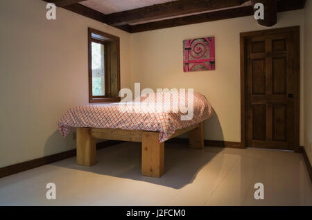 Letto queen size sul telaio in legno nella camera da letto degli ospiti all'interno di un cottage in stile casa di registro Foto Stock