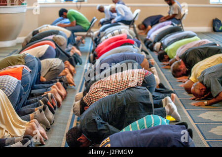 Uomini musulmani prostrarsi in 'Sujood' posizione di preghiera con le loro facce di Islam moquette a motivi geometrici a Venerdì pomeriggio la preghiera durante i servizi religiosi a un Anaheim, CA, la moschea. Foto Stock