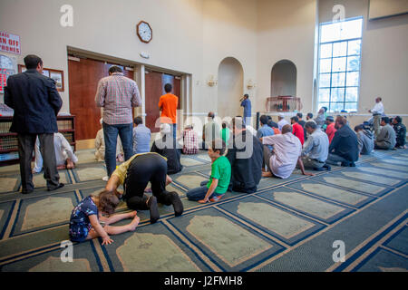 Uomini musulmani prostrarsi in 'Sujood' posizione di preghiera con le loro facce di Islam moquette a motivi geometrici a Venerdì pomeriggio la preghiera durante i servizi religiosi a un Anaheim, CA, la moschea. Nota ragazzo e una ragazza adoratori. Foto Stock