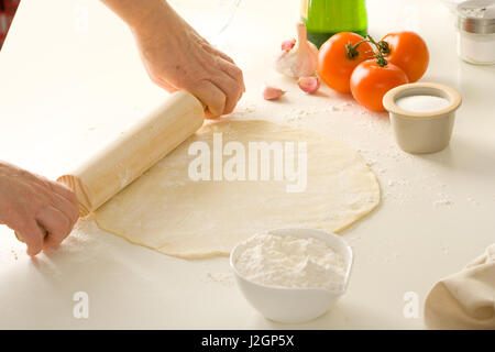 Impasto per pizza su un tagliere con ingredienti e matterello. Foto Stock