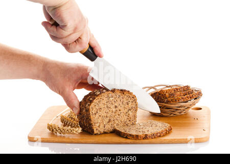 Pane fresco. La Crusca per affettare il pane su un tagliere. taglio mani il pane sulla tavola di legno Foto Stock