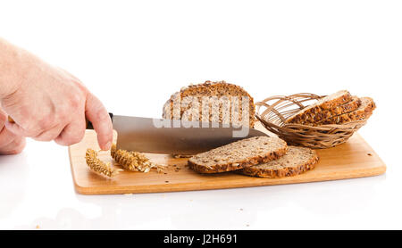 Pane fresco. La Crusca per affettare il pane su un tagliere. taglio mani il pane sulla tavola di legno Foto Stock