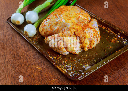 Materie intero pollo marinato con aglio, timo e limone vicino sul tavolo. Foto Stock