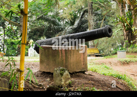 Nero antico cannone di ferro in appoggio sul blocco di pietra bianca utilizzata per la difesa indietro nella storia poste tra gli alberi del bosco verde. Foto Stock