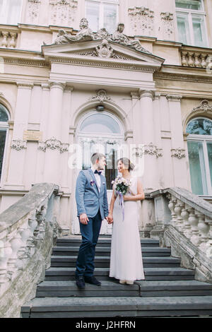 Attraente enloved sposa giovane scendendo da antiche scale in prossimità del vecchio palazzo austriaco. Foto Stock