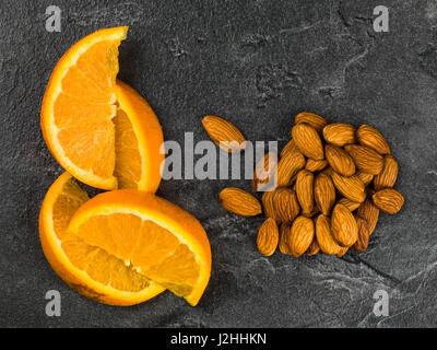 Succo di arancia con mandorla dadi contro uno sfondo nero Foto Stock