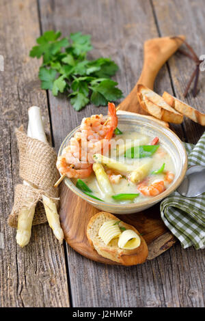 La Crema di zuppa di asparagi con i gamberi fritti e neve piselli, servita con crostini di baguette con burro rotoli Foto Stock