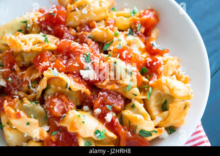 Tortellini freschi fatti in casa con salsa di pomodoro e le erbe tritate e il parmigiano reggiano Foto Stock