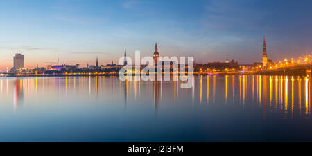 Old Riga dello skyline di notte. Città illuminata dopo il tramonto. Vista panoramica sul fiume Daugava Foto Stock