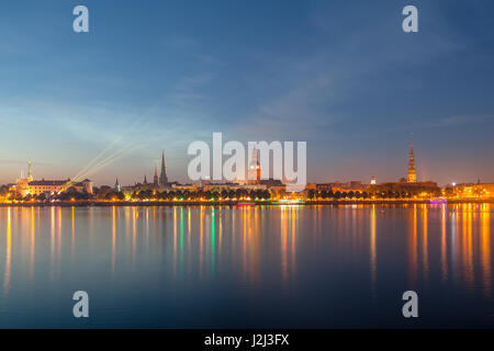 Old Riga dello skyline di notte. Città illuminata dopo il tramonto. Vista panoramica sul fiume Daugava Foto Stock