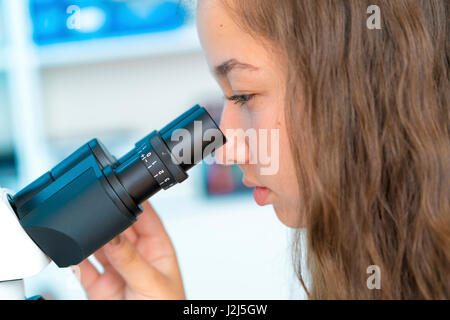 Donna scienziato usando microscopio. Foto Stock