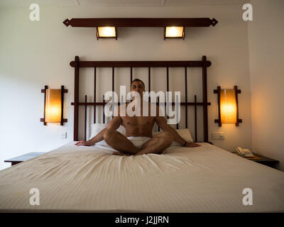 Giovane uomo yoga rilassante nel letto dopo il risveglio al mattino. Foto Stock