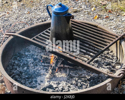 Tè blu bollitore d' acqua sulla griglia in una buca per il fuoco in campeggio Foto Stock