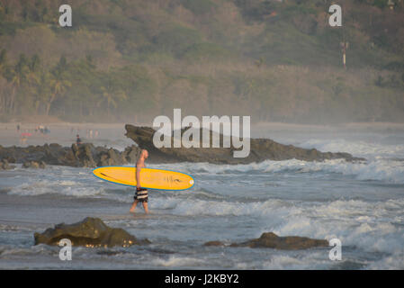 Un surfista passeggiate nelle onde in Playa Santa Teresa in Costa Rica della costa del Pacifico. Foto Stock