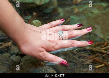 Donna di mano acqua toccante Foto Stock
