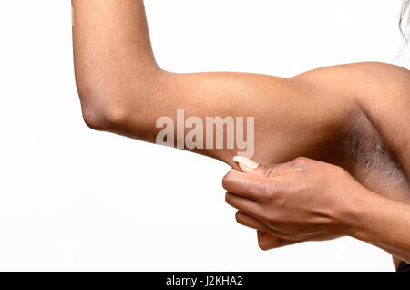 Giovane donna africana visualizzando la pelle allentata o flab a causa dell'invecchiamento sul suo braccio superiore stringere tra le dita, vista ravvicinata Foto Stock