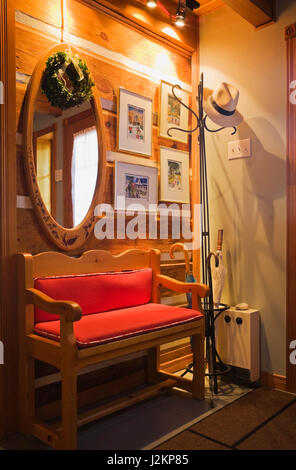 Seduta in legno panca con cuscini rossi nel lato della porta d'ingresso corridoio interno un Canadiana cottage in stile casa di registro Foto Stock