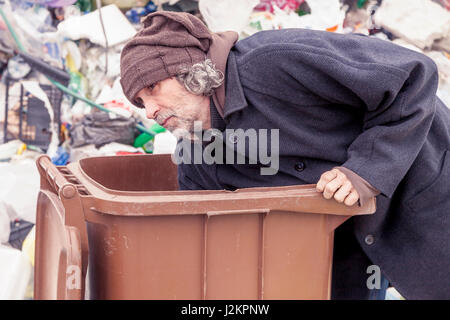 Senzatetto rummages nella pattumiera di discariche Foto Stock