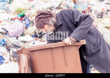 Senzatetto rummages nella pattumiera di discariche Foto Stock