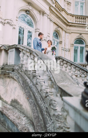 Attraente sposa giovane in amore scendendo da antiche scale in prossimità del vecchio palazzo austriaco Foto Stock