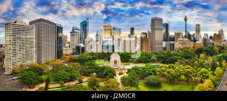 Sydney hyde park e il CBD cityline su una luminosa giornata autunnale. Alberi colorati intorno ANZAC memorial e alte torri della città. Foto Stock